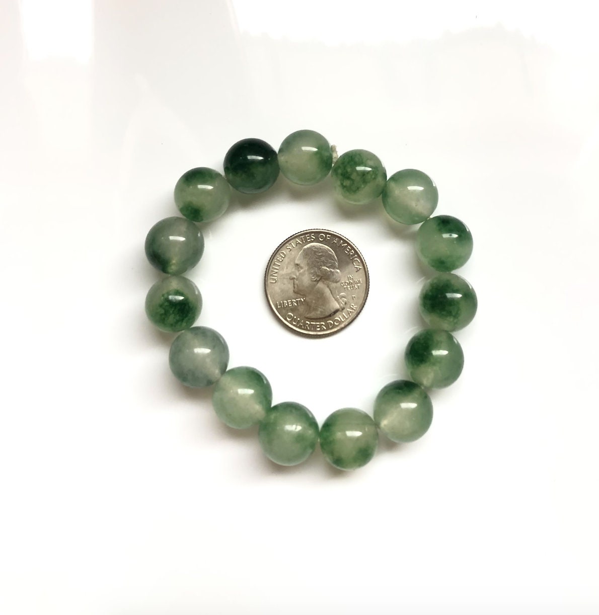 Moss agate jade bracelet next to a US quarter coin for bead size comparison