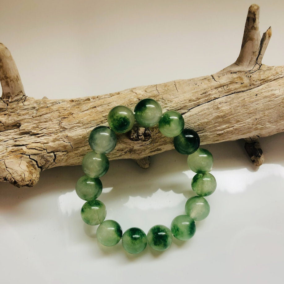 large green jade bead bracelet with stretch lay on a piece of wood