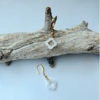 Close-up of white jade clover earrings showing real Chinese jade texture and gold hook attachment on a branch