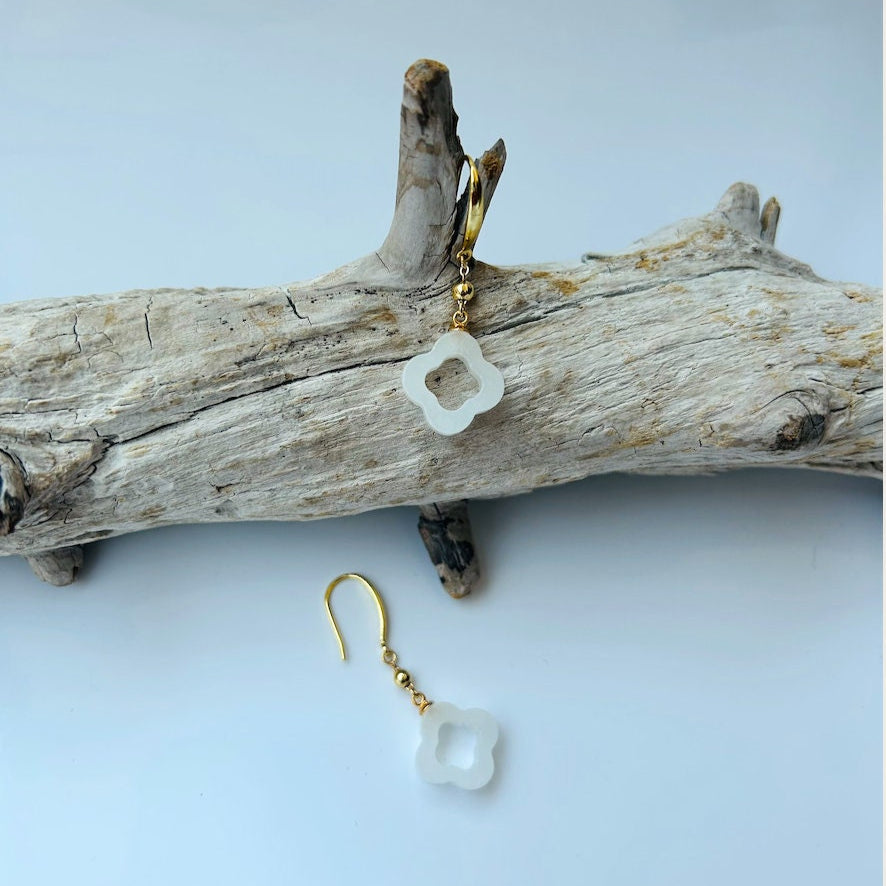 Close-up of white jade clover earrings showing real Chinese jade texture and gold hook attachment on a branch