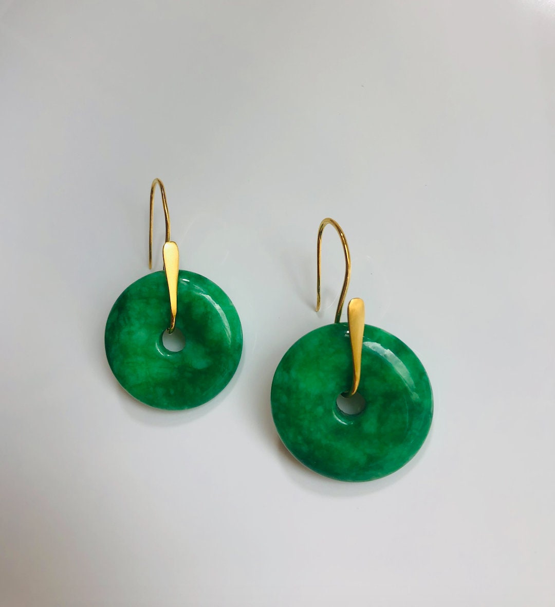Close-up of glossy emerald green jade and gold hook detail on earrings

