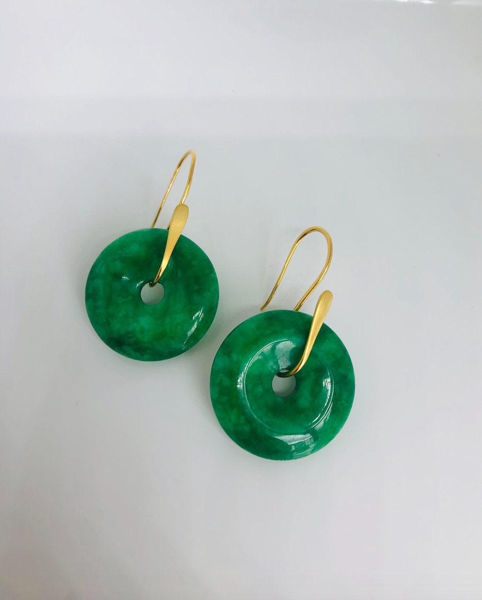 A pair of dark green jade donut earrings with 18k gold plating on the top and bottom, displayed against a white background.