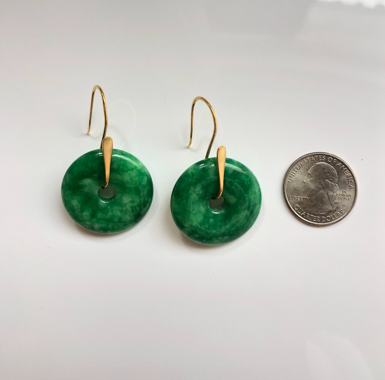Real jade earrings next to a coin to show size of jade discs