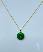 Close-up of polished jade circle pendant with 18k gold necklace loop