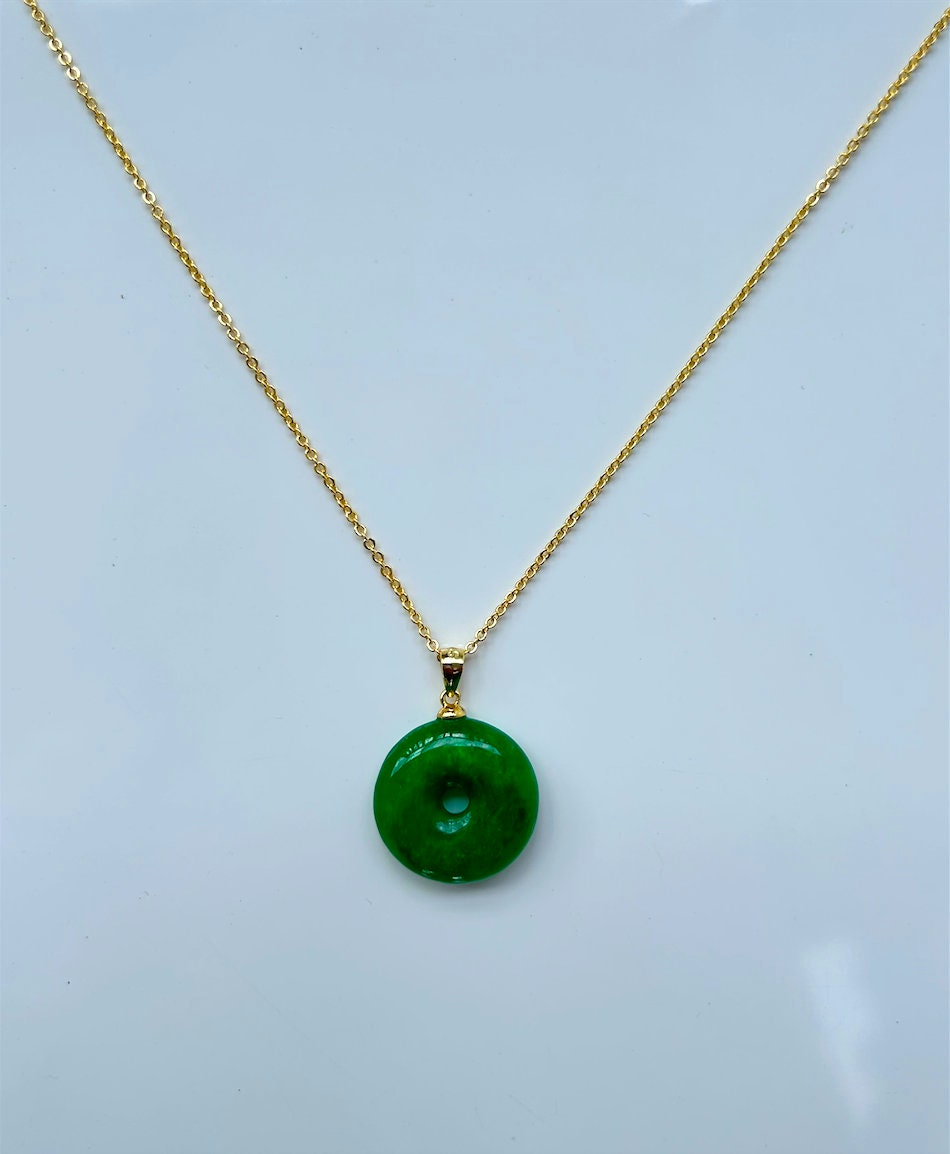 Close-up of polished jade circle pendant with 18k gold necklace loop