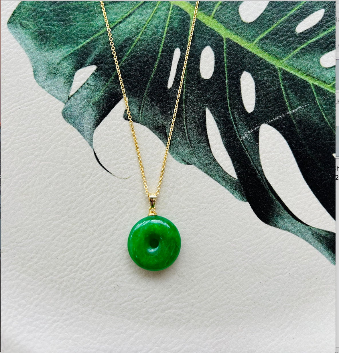 jade donut pendant showing smooth stone surface on a leather plate with leaf decoration