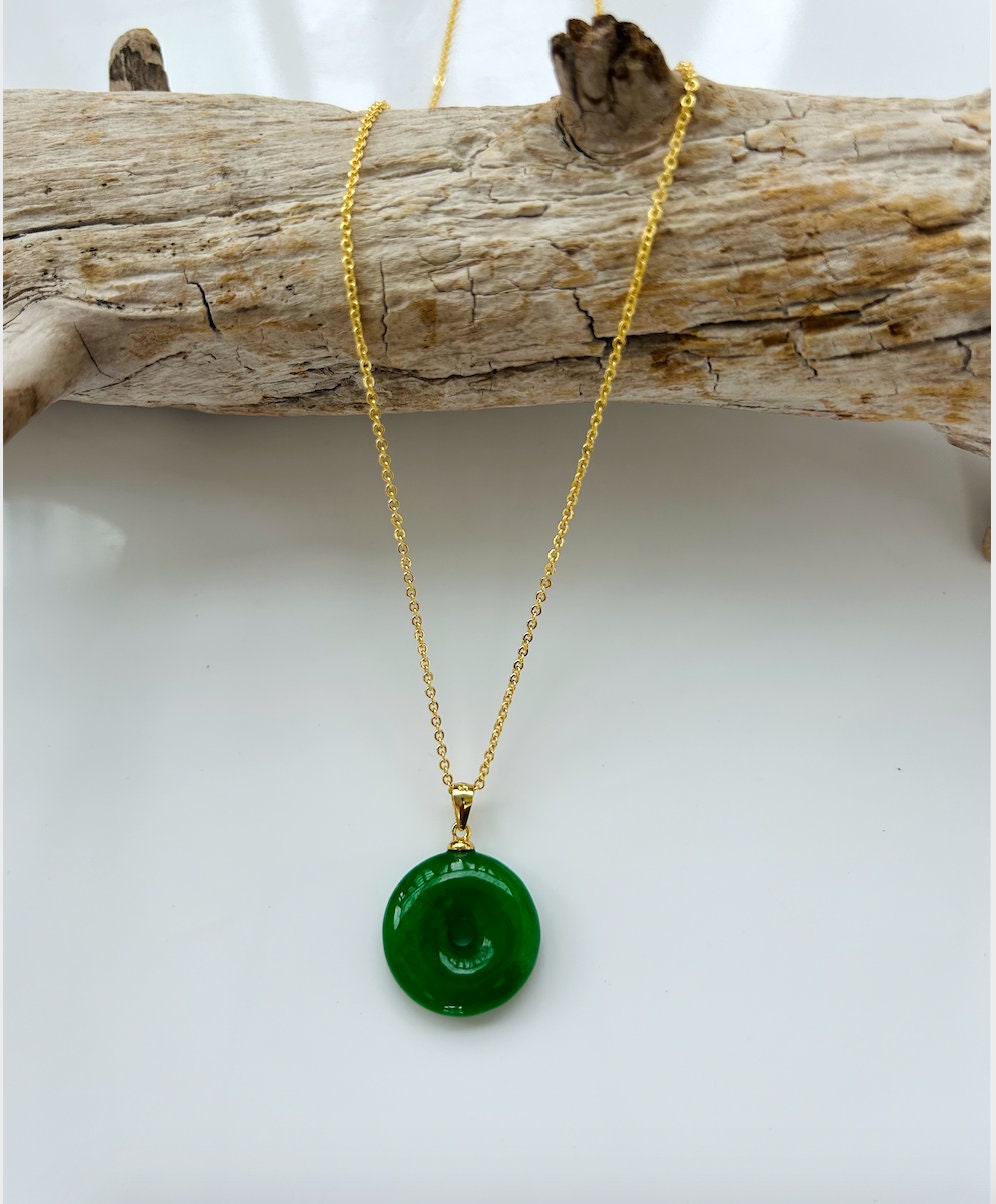 Front view of minimalist green jade donut necklace with 18k gold chain on a wood stalk