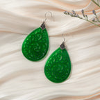Lace-inspired 925 silver earrings with dark green jade teardrops in traditional Chinese style on a silk cloth