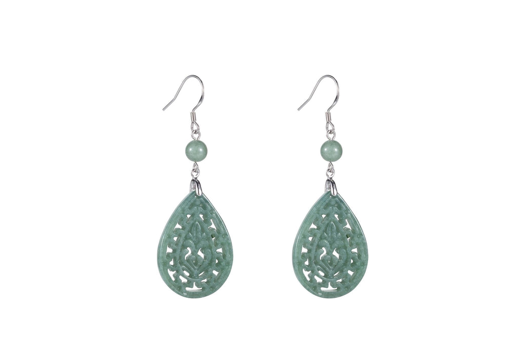 A pair of light green jade teardrop earrings with intricate cut-out patterns, suspended from silver hooks.