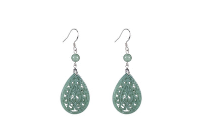 A pair of light green jade teardrop earrings with intricate cut-out patterns, suspended from silver hooks.