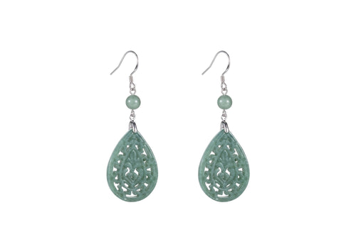 A pair of light green jade teardrop earrings with intricate cut-out patterns, suspended from silver hooks.