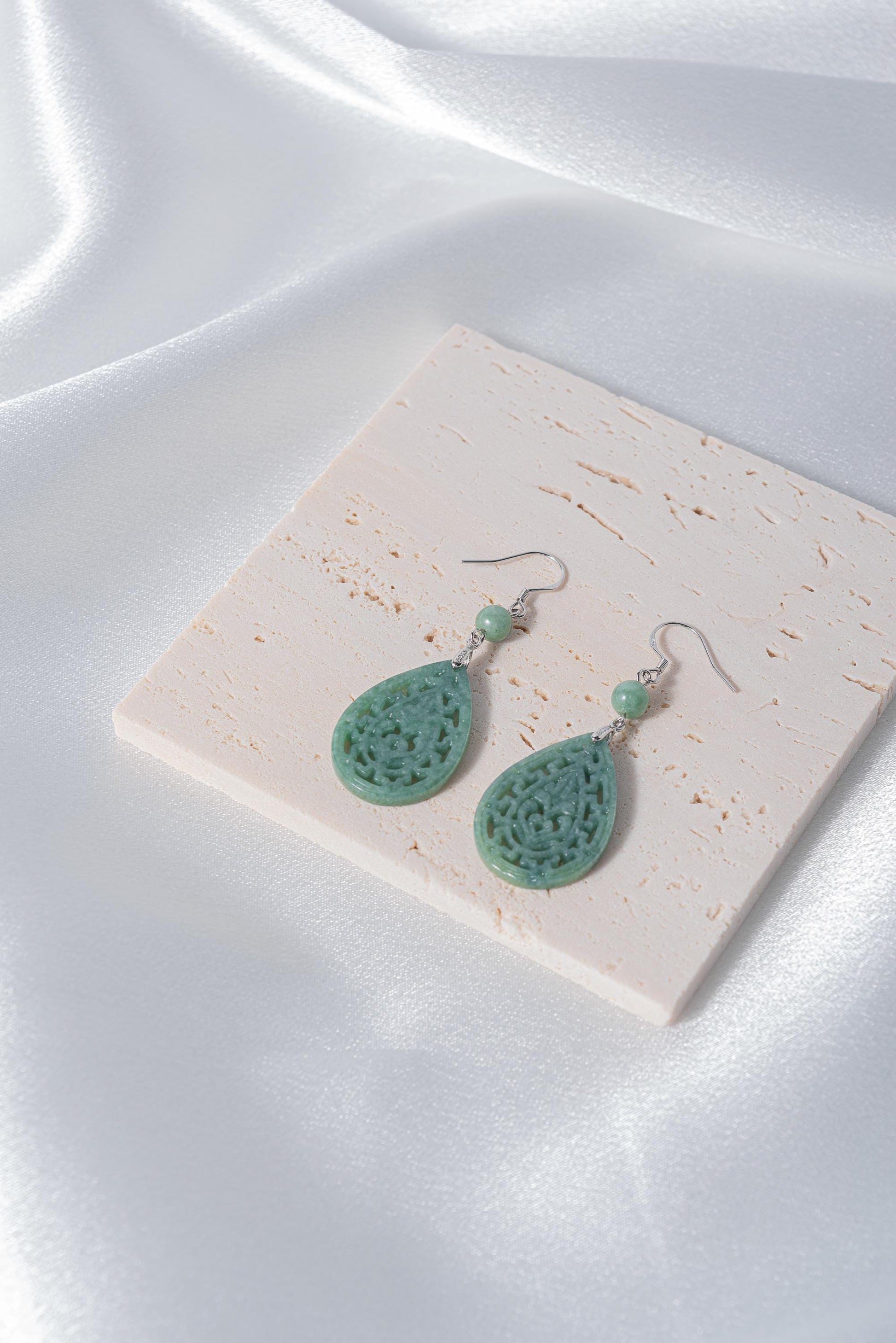 Side angle showing silver lace setting around light green jade teardrop stone