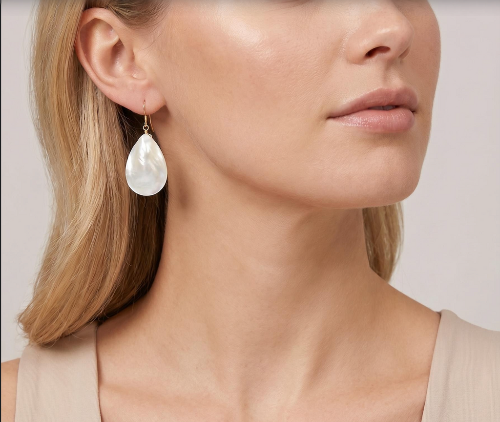 Close-up of a woman wearing a pearl earring with a plain background