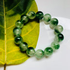Side angle of Chinese jade bracelet with round moss agate beads and elastic cord on a leaf