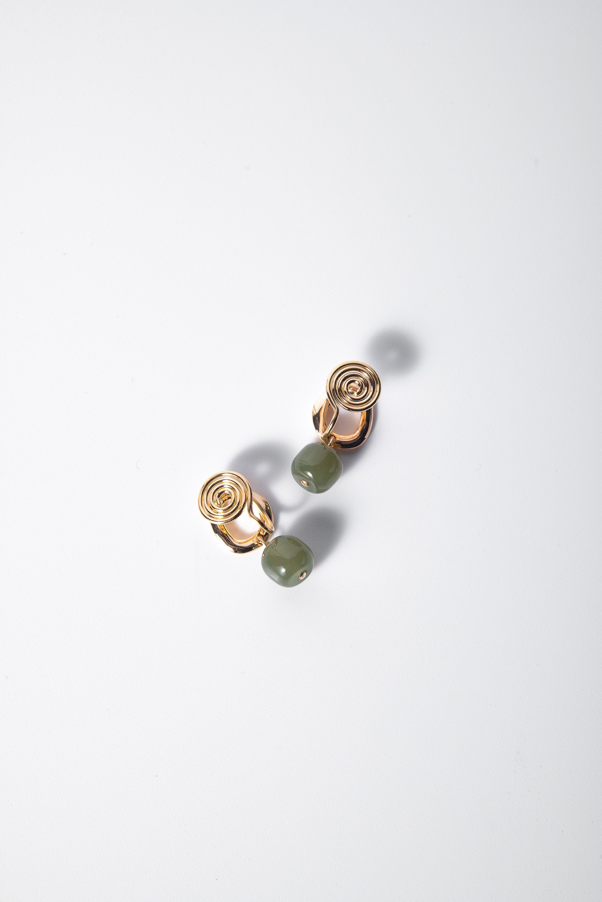 side angle of hanging green jade clip-on earrings showing natural jade texture and gold details