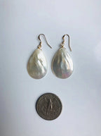 Teardrop-shaped earrings on a light gray background with a coin for scale.