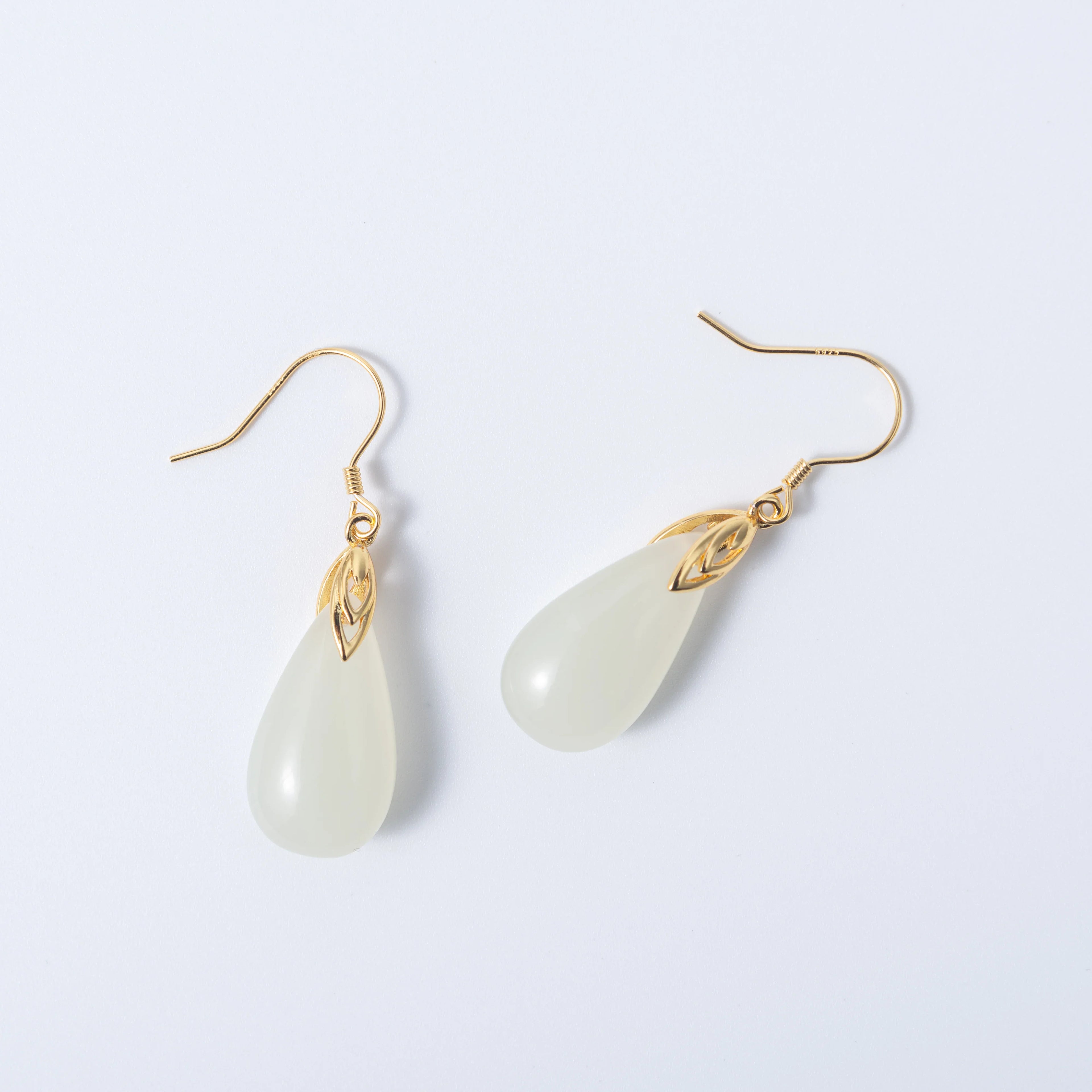 Teardrop-shaped earrings with gold hooks on a light gray background