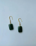 A pair of dark green rectangle-shaped jade earrings with gold ear wires, displayed against a white background.