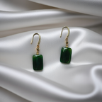 cube-shaped jade drop earrings with gold detail on a white silk fabric