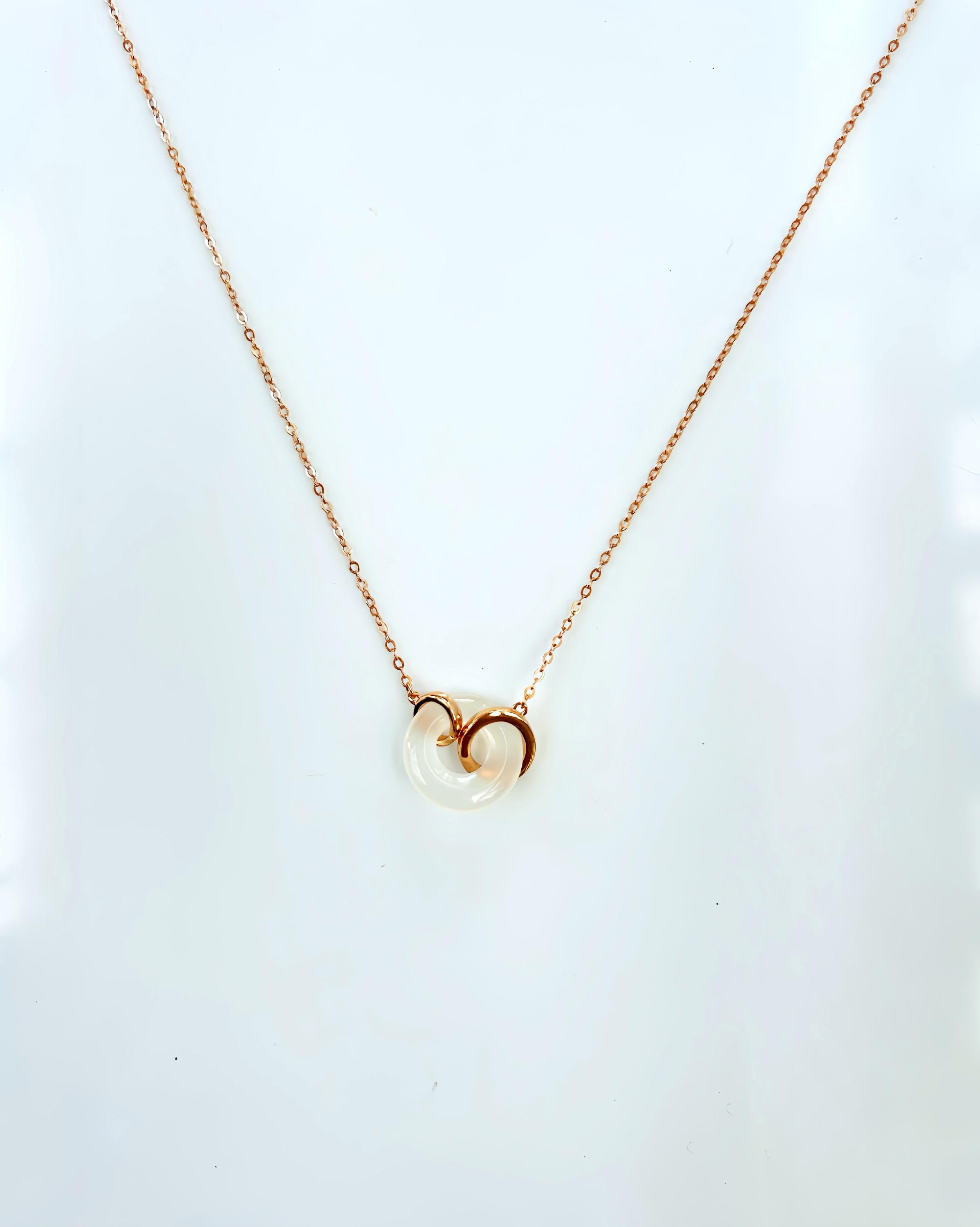 Close-up of genuine white jade circle pendant on delicate rose gold chain

