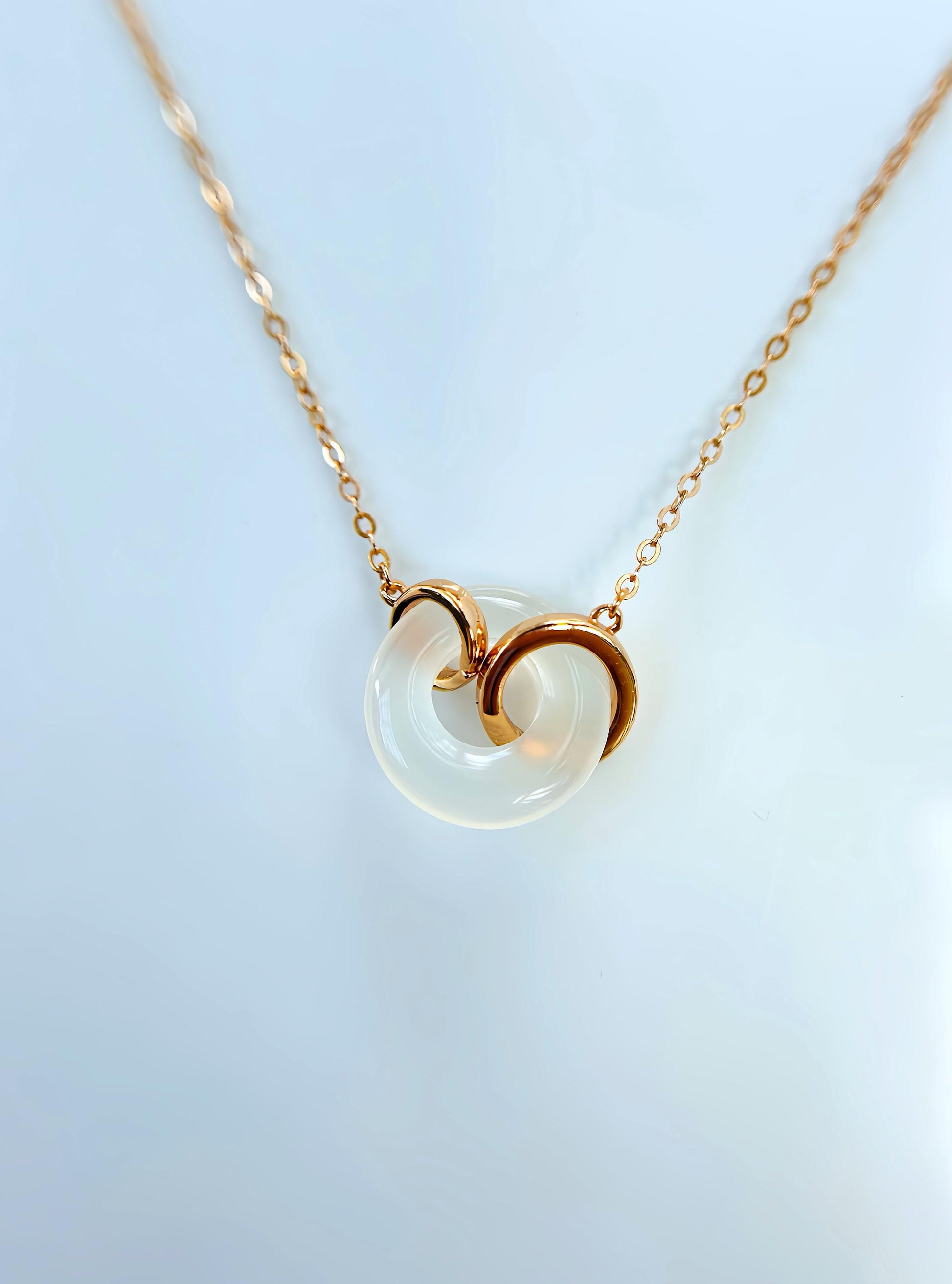 A rose gold necklace with a white jade circular pendant, featuring a simple yet elegant design.