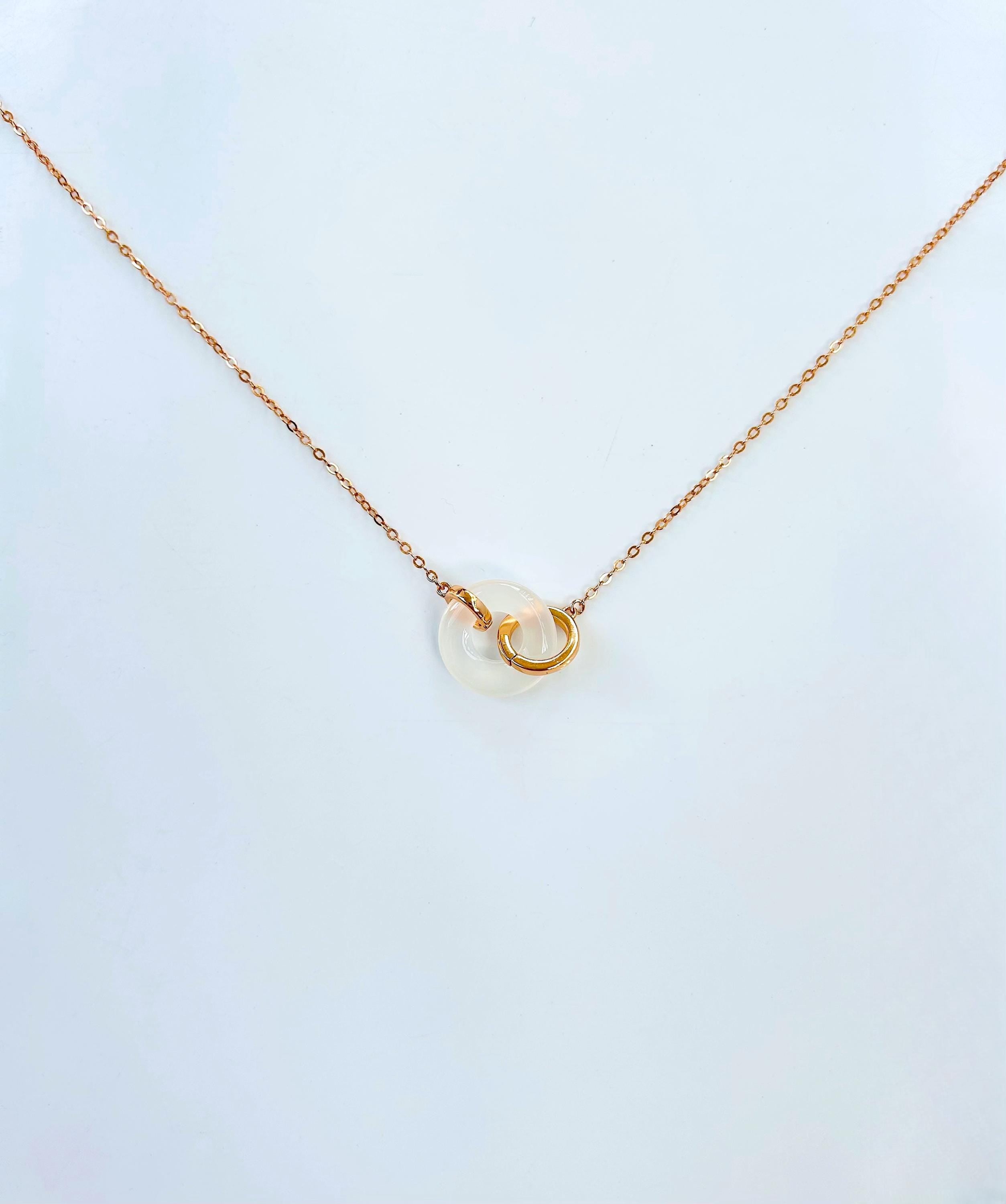 Side angle showing polished white jade circle pendant and rose gold chain


