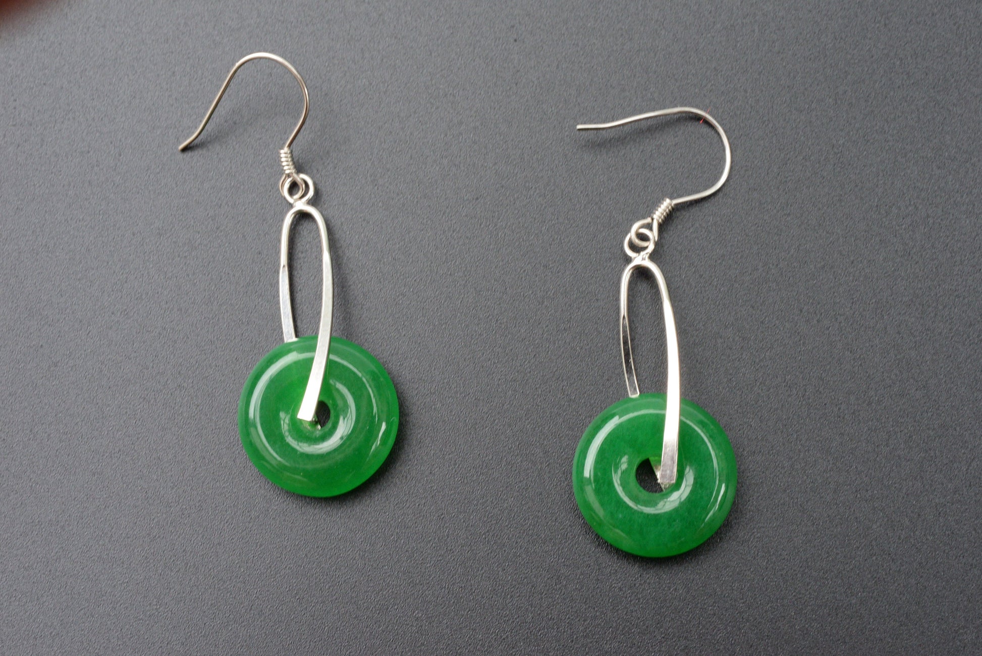 Close-up of round green jade earrings showing natural stone texture and silver hardware