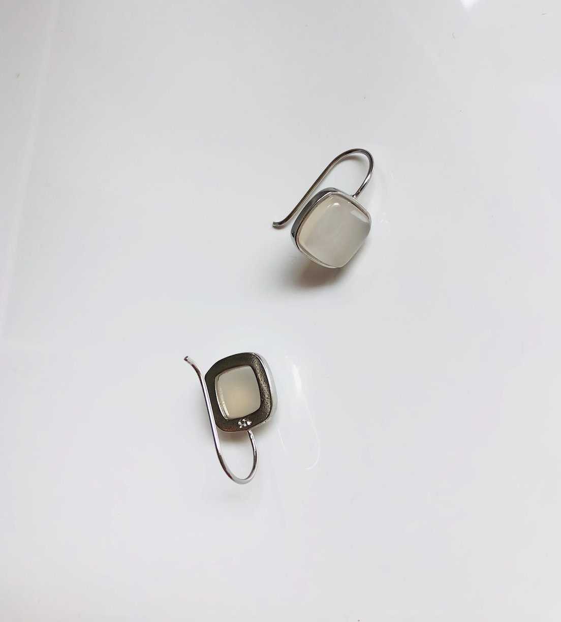 back view of white jade square dangle earrings hanging from polished 990 silver hooks