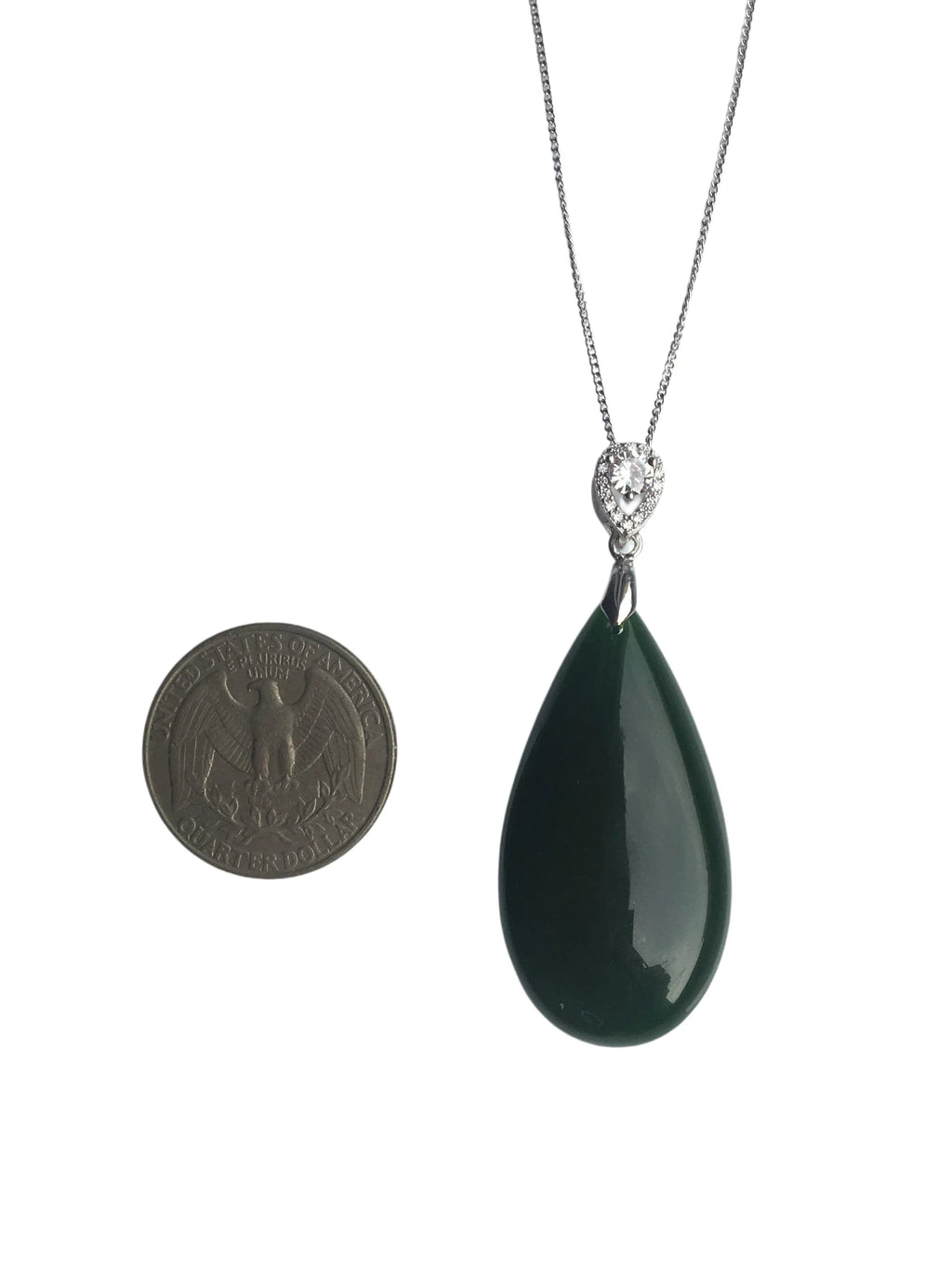 Teardrop-shaped green pendant on a chain with a coin for scale on a white background
