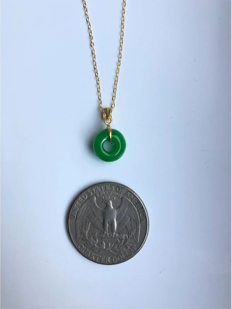 Jade circle pendant next to a coin to show size of the donut charm