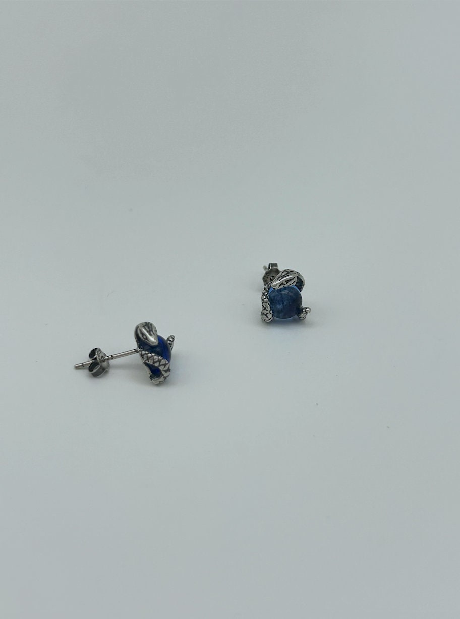 Back view of small silver snake eye studs with deep blue topaz-style gemstone center