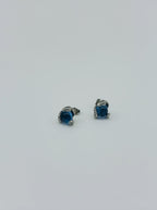 Side view of small silver snake eye studs with deep blue topaz-style gemstone center