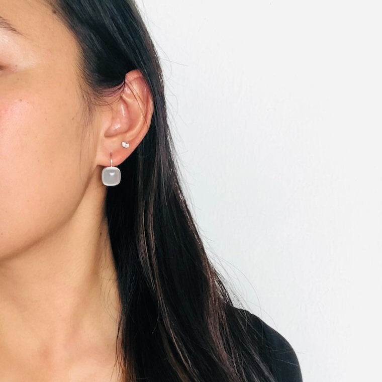 Model wearing square white jade earrings with sterling silver dangle design