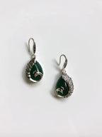 Close-up of natural jade teardrop earrings with detailed silver peacock design