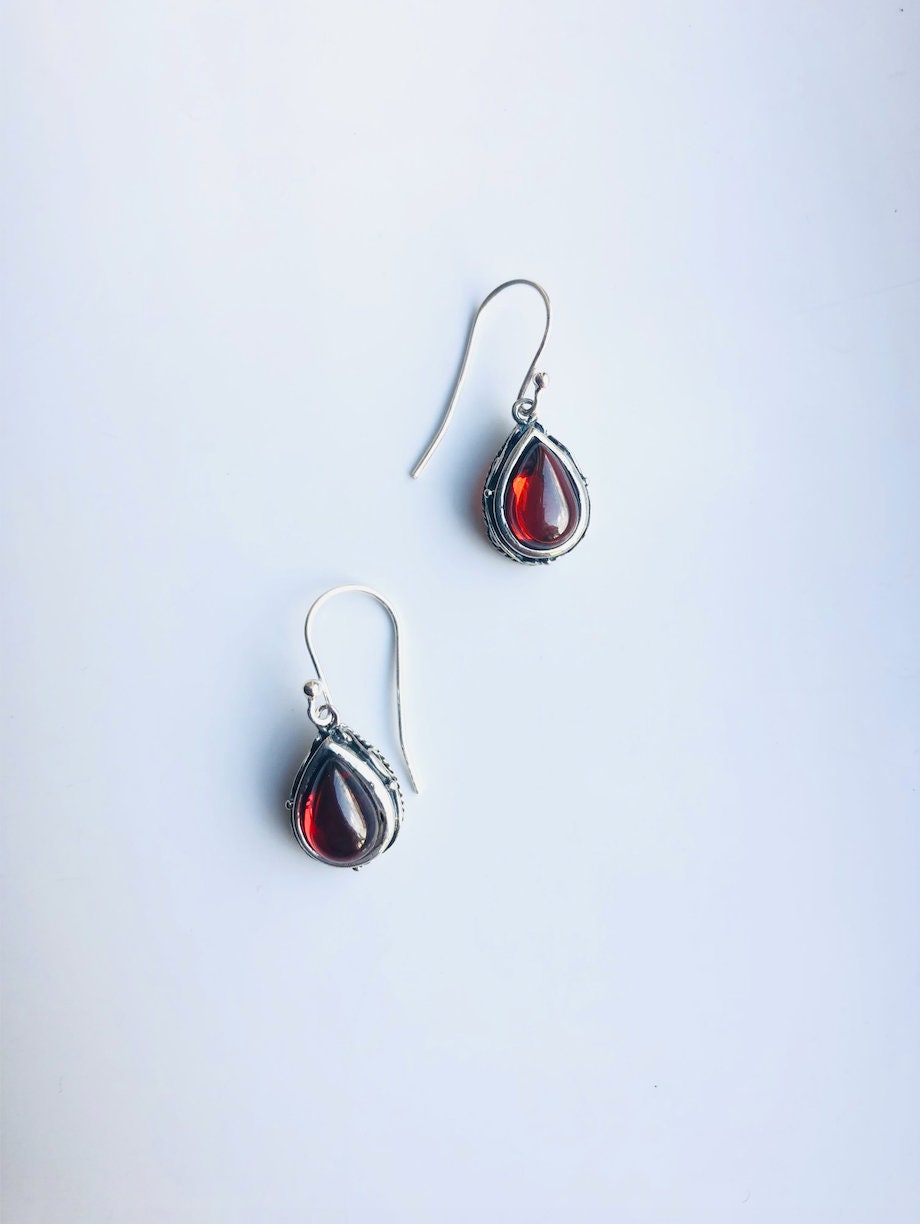 Red exotic ruby jewelry with lace design and silver hooks against the white background