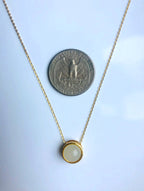 White jade pendant necklace next to coin for size reference