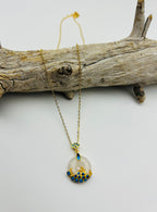 Front view of white jade circle pendant with 18k gold and blue wave ceramic