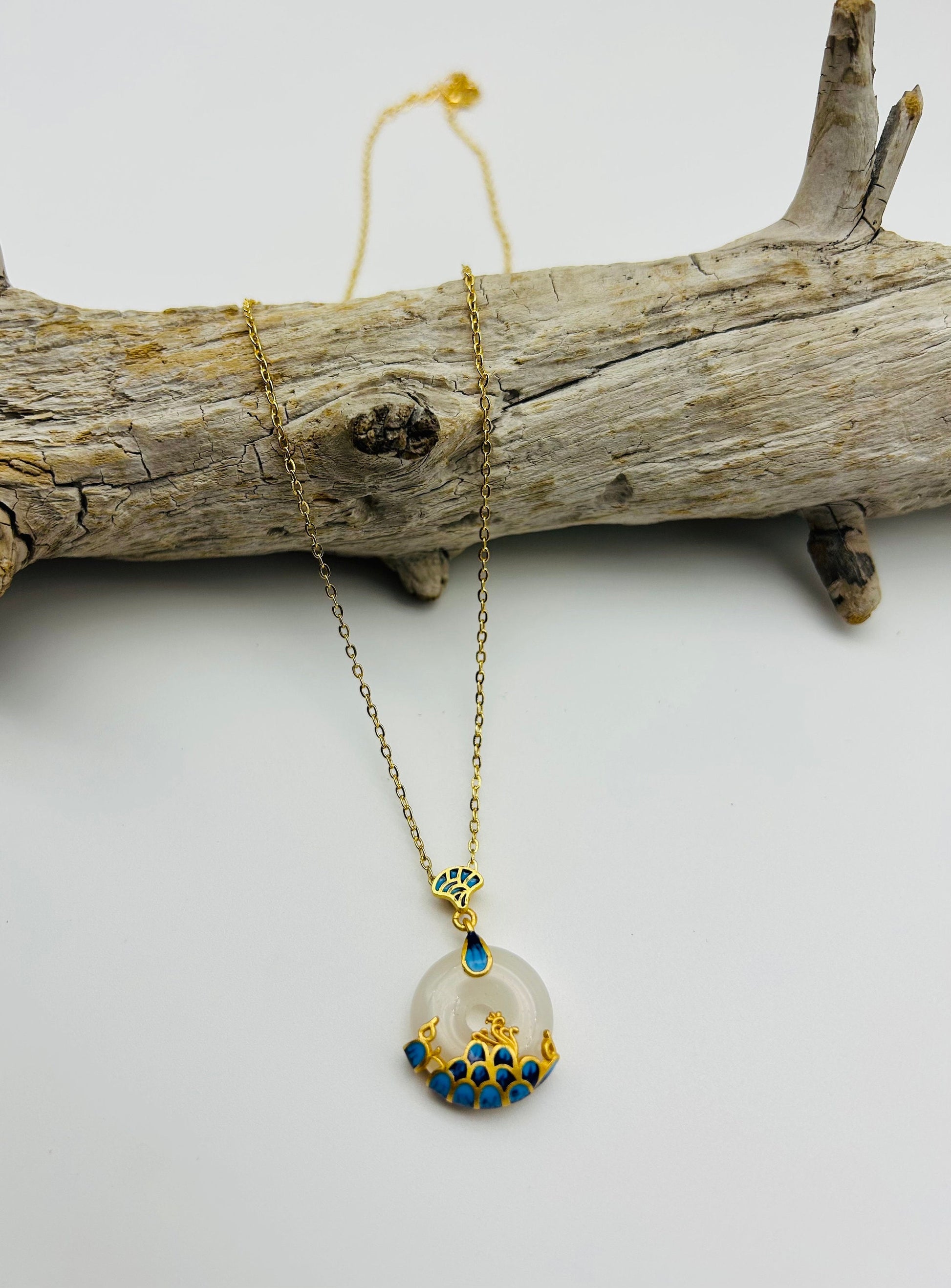 Front view of white jade circle pendant with 18k gold and blue wave ceramic