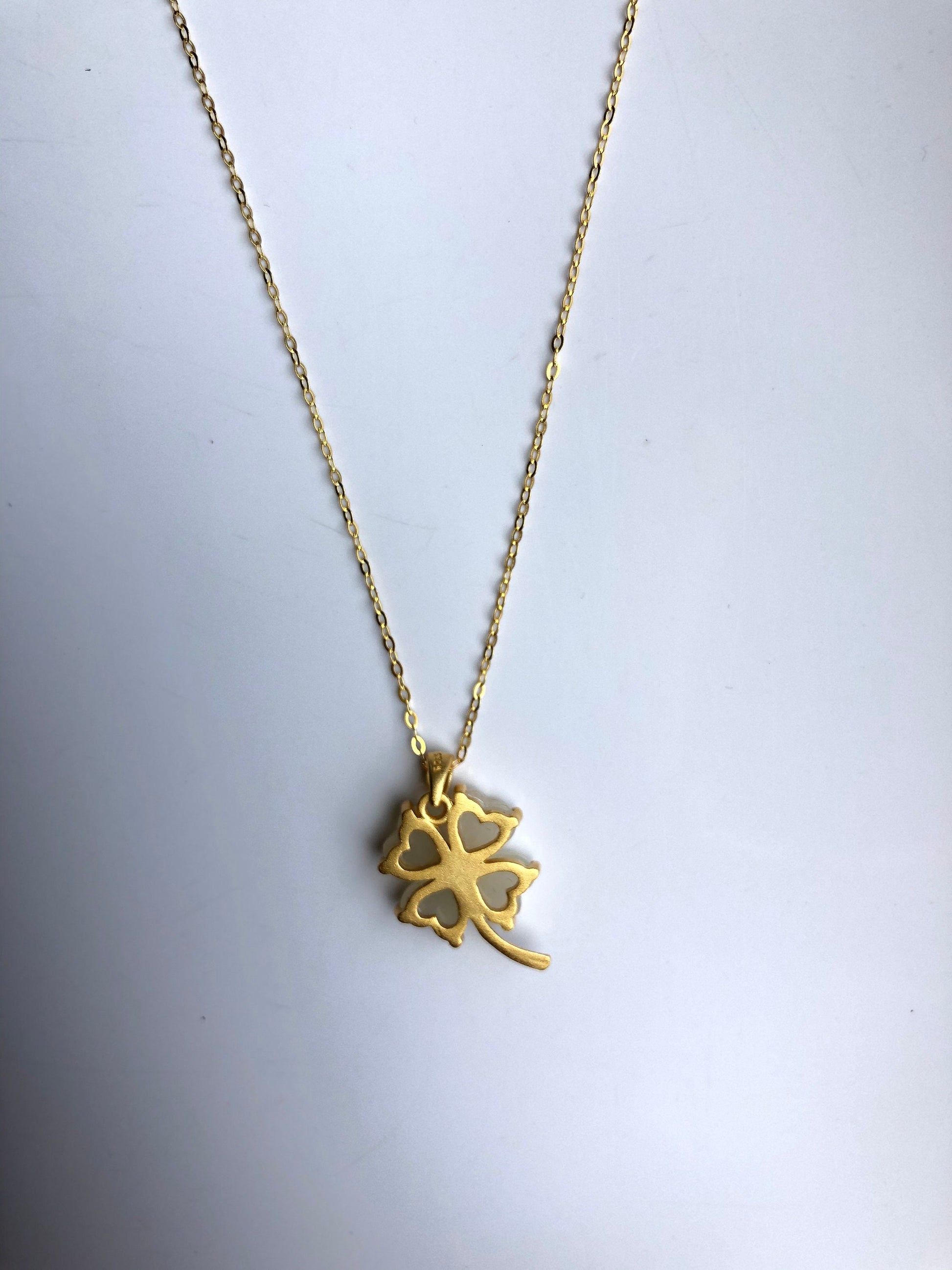 Back of white jade pendant showing smooth finish and gold loop