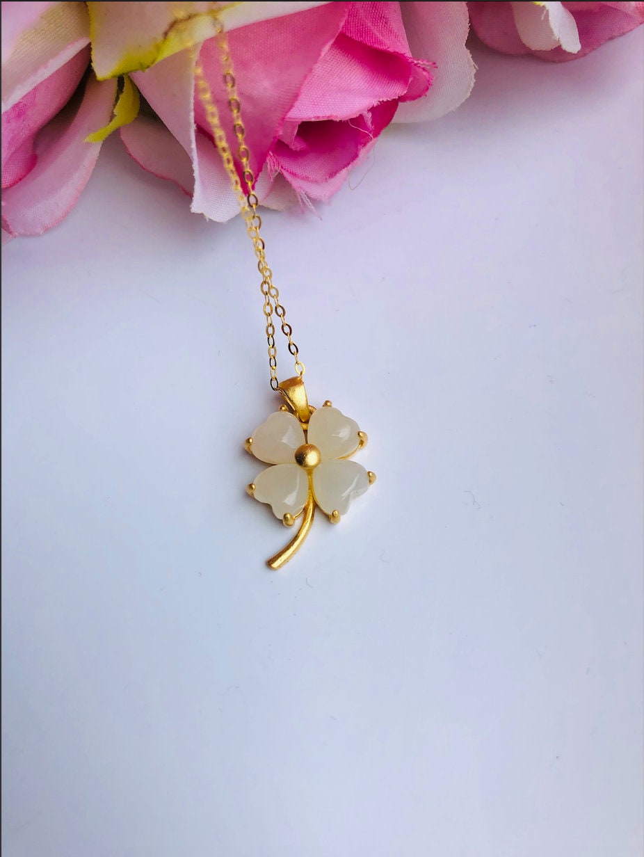 Close-up of genuine white jade clover pendant set on a gold chain