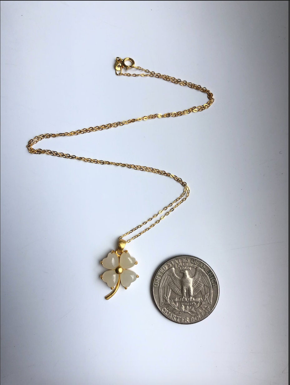 White jade clover pendant necklace shown next to coin for size reference