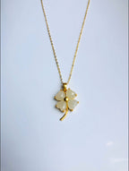 A white jade clover pendant on a gold-plated chain necklace against a white background.