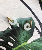 gold-plated jade earrings showing polished jade and gold settings on a green leaf