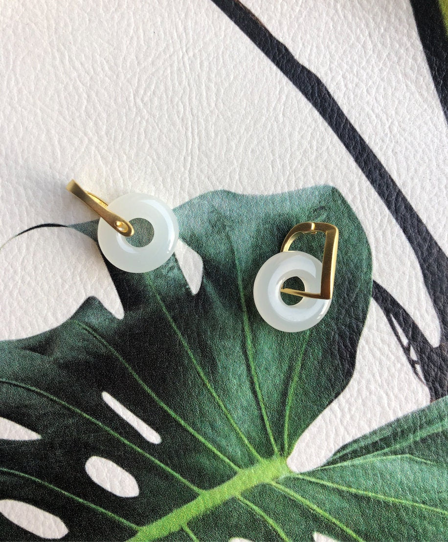 gold-plated jade earrings showing polished jade and gold settings on a green leaf