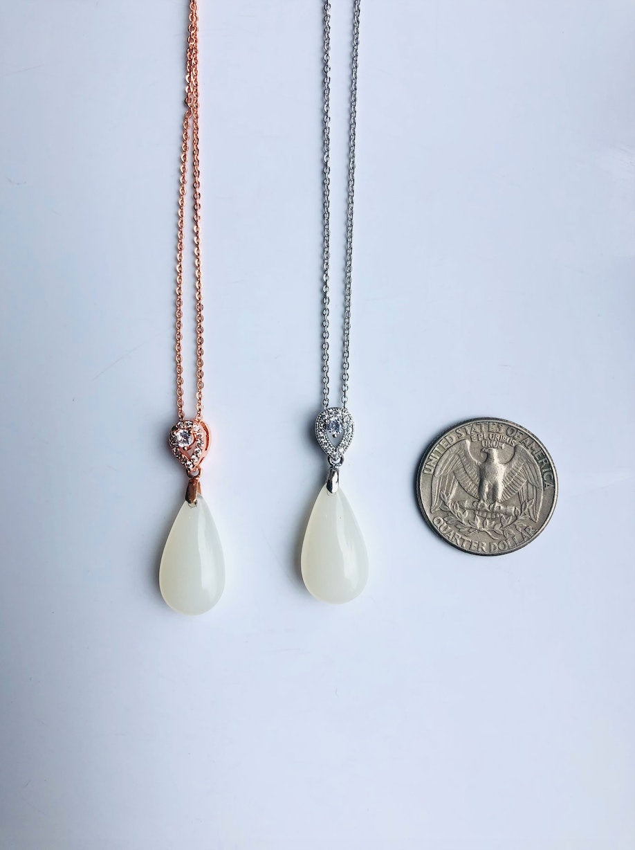 Size comparison of white jade teardrop necklace shown next to a US quarter coin