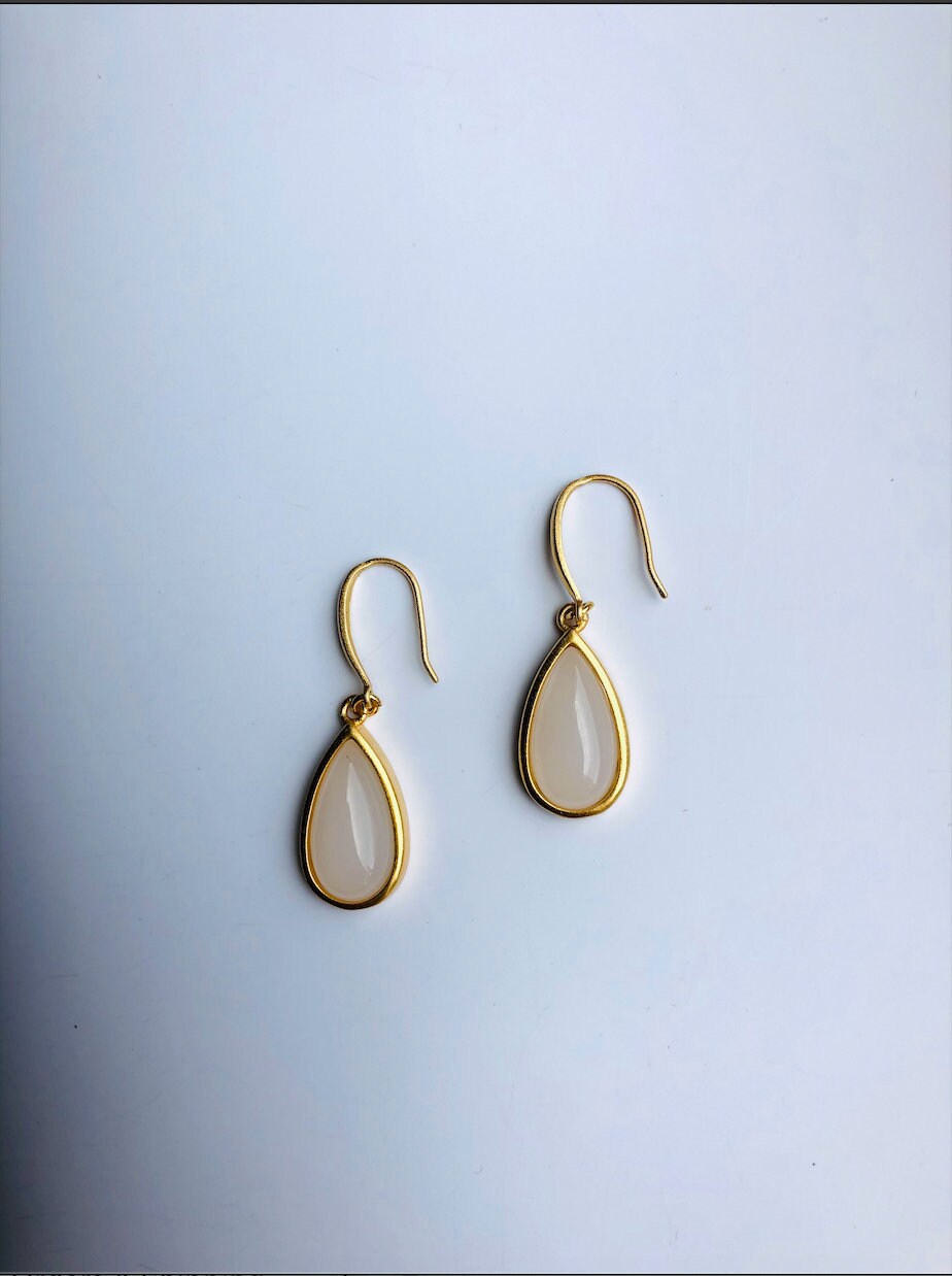Close-up of real white jade earrings with 18k gold accents