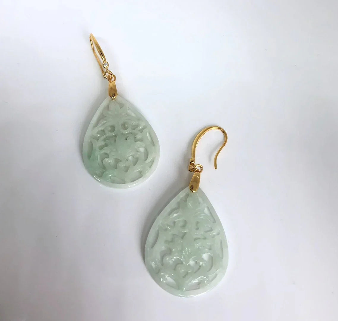 Teardrop-shaped green earrings with gold hooks on a white background