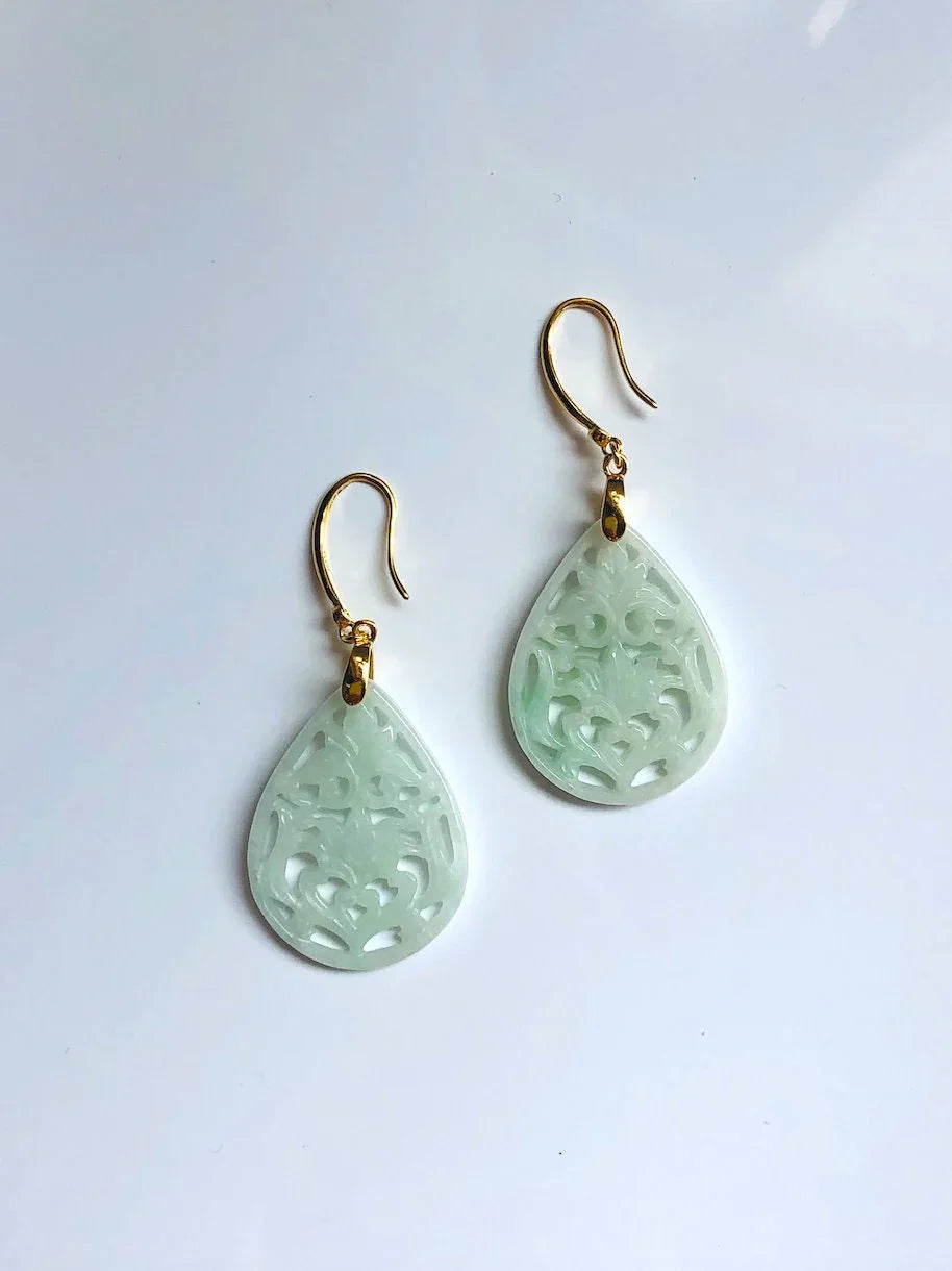 Pair of green teardrop earrings with gold hooks on a white background